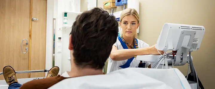 Vårdpersonal samtalar med en person i ett undersökningsrum.