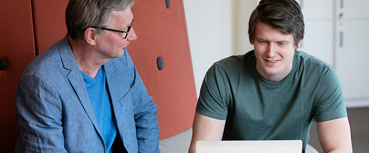 Två personer pratar med varandra vid ett bord.